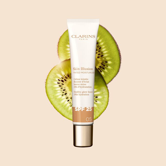 Plan produit du tube de 40&nbsp;ml du perfecteur de teint Skin Illusion Tinted Moisturizer teinte&nbsp;05, plac&eacute; &agrave; c&ocirc;t&eacute; de tranches de kiwi.
