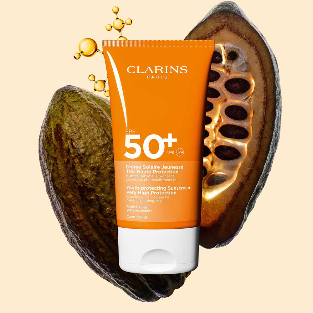 Afbeelding van Clarins Youth-protecting Sunscreen Very High Protection SPF 50+ voor het lichaam tussen collageenmoleculen en cacaobonen.