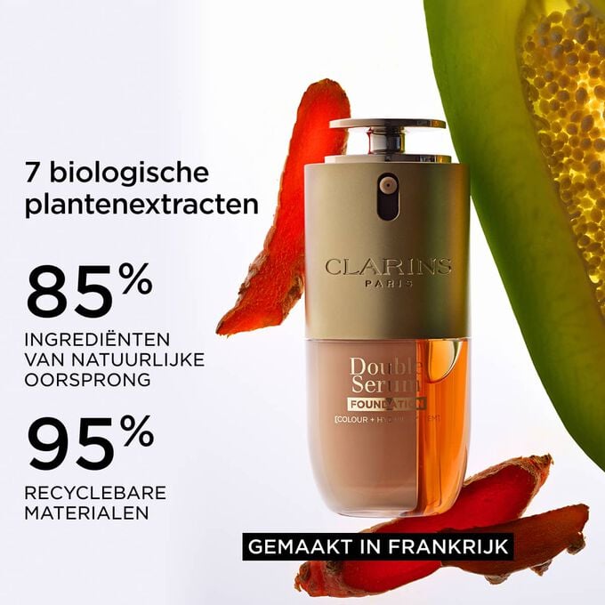 Packshot van Double Serum Foundation naast kurkuma en papa&iuml;ne, om de nadruk te leggen op de natuurlijke ingredi&euml;nten en het Made in France-label
